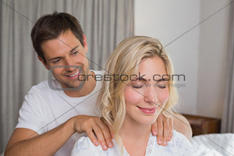 Smiling man massaging woman's shoulders