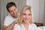 Smiling young man massaging woman's shoulders