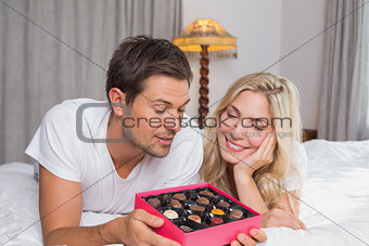 Young couple with candies resting in bed