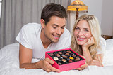 Relaxed young couple with candies in bed
