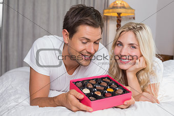 Relaxed young couple with candies in bed