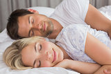 Couple lying in bed with eyes closed