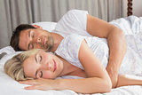Relaxed couple lying in bed with eyes closed
