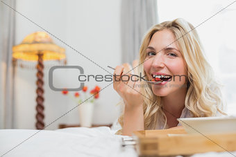 Happy young woman having food in bed