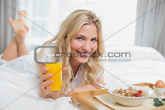 Happy young woman having breakfast in bed