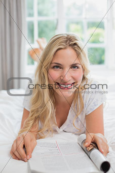 Beautiful young woman reading magazine in bed
