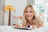 Beautiful casual woman reading magazine in bed