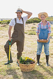 Full length of a smiling couple with vegetables in field