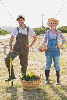 Full length of smiling couple with vegetables in field