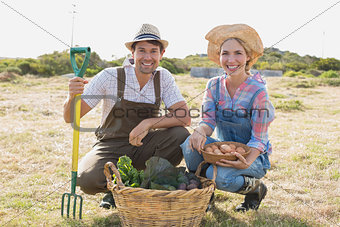 Smiling young couple with vegetables in field