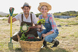 Smiling young couple with vegetables in field