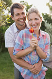 Smiling couple holding a flower in park