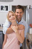 Young man embracing woman from behind in kitchen