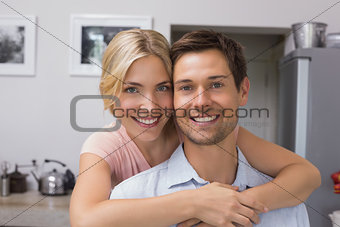 Smiling woman embracing man from behind in kitchen