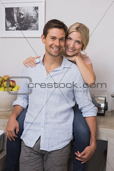 Smiling woman embracing man from behind at home