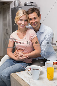 Man embracing woman at breakfast table at home