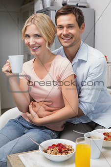 Man embracing woman at breakfast table at home