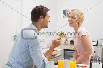 Couple looking at each other while having breakfast at home