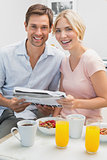Couple reading newspaper while having breakfast at home