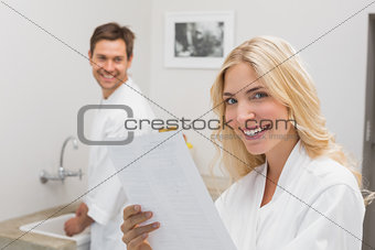 Smiling woman holding document with man in kitchen