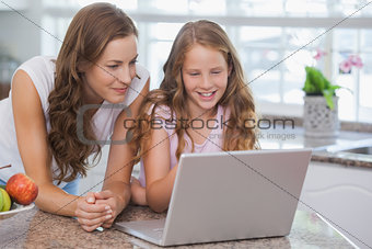 Girl and mother using laptop in house