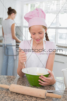 Girl helping her mother prepare food in kitchen