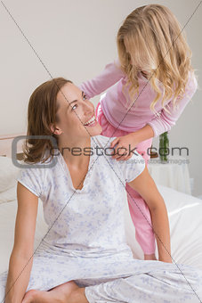Happy woman and girl playing in bedroom