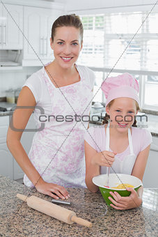 Young girl helping mother prepare food in kitchen