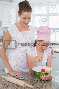 Young girl helping mother prepare food in kitchen