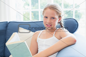 Relaxed girl reading book on sofa in living room