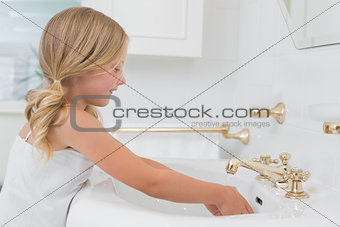Side view of a cute girl washing hands at washbasin