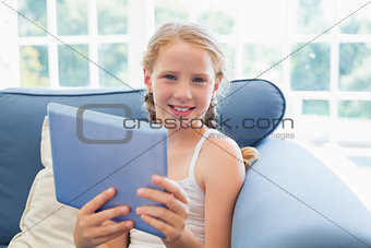 Young girl using digital tablet on sofa in living room