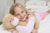 Young girl resting in bed with stuffed toy