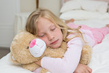 Young girl sleeping with stuffed toy in bed
