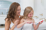 Mother and daughter brushing teeth in bathroom