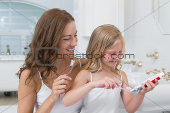 Mother and daughter brushing teeth in bathroom