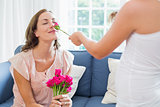 Mother smelling flowers with kid in living room