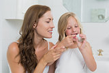 Mother and daughter putting cream on face