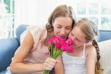 Mother and daughter smelling flowers in the living room