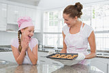 Smiling woman and girl with freshly prepared cookies in kitchen
