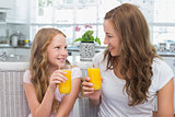Mother and daughter with orange juice glasses in kitchen