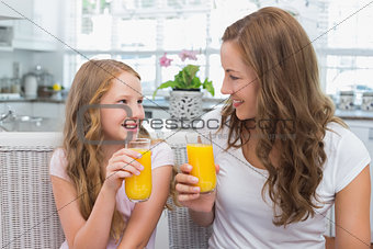 Mother and daughter with orange juice glasses in kitchen