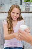 Happy young girl receiving a glass of milk