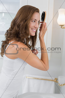 Side view of a beautiful young woman brushing her hair