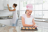 Girl looking at freshly prepared cookies with mother in kitchen