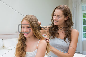 Beautiful young woman brushing little girl's hair