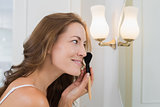 Side view of a beautiful woman applying make-up