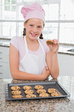 Smiling young girl enjoying cookies in kitchen