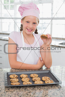 Smiling young girl enjoying cookies in kitchen