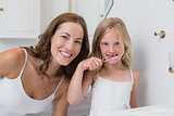 Portrait of mother with daughter brushing teeth